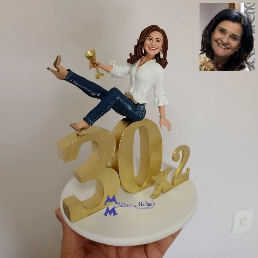 Boneca de aniversário 30x2 com taça dourada Boneca de biscuit sentada sobre números dourados 30x2 brindando com taça dourada, de blusa branca e jeans