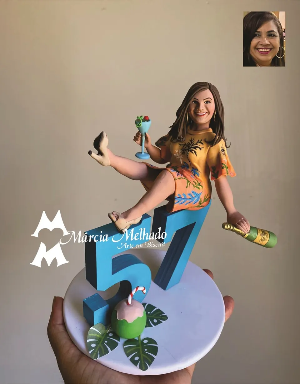 Boneca de aniversário 57 anos com drink e coco Boneca de biscuit de vestido tropical laranja sentada no número 57 azul, com taça de drink, garrafa, coco e folhas na base