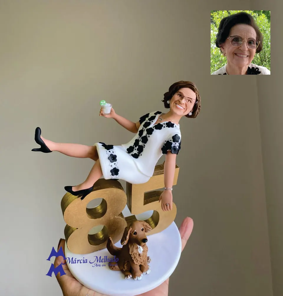 Boneca de aniversário 85 anos sentada no número dourado com cachorro Boneca de biscuit de senhora de óculos com vestido branco florido sentada no número 85 dourado, com drinque e cachorro.