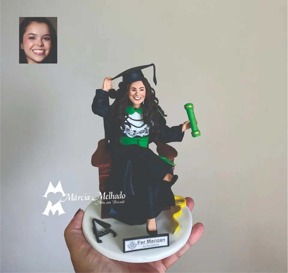 Boneca de formatura em nutrição com fita métrica e adipômetro Boneca de biscuit formanda de nutrição sentada em poltrona, segurando o capelo e o canudo verde