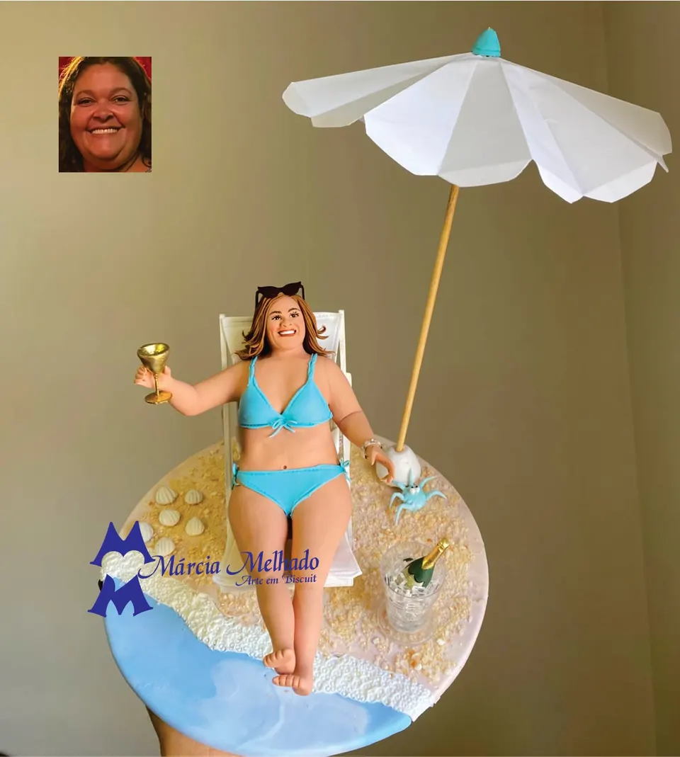 Boneca de praia na espreguiçadeira com guarda-sol e champanhe Boneca de biscuit de biquíni azul deitada em espreguiçadeira na areia, com taça, guarda-sol branco e balde de champanhe