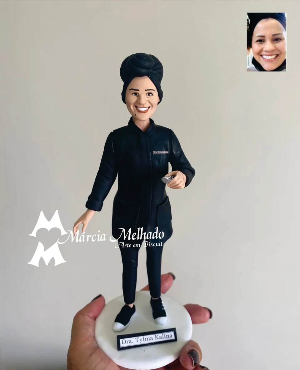 Boneca doutora de jaleco preto e turbante com instrumento na mão Boneca de biscuit de jaleco preto e turbante preto segurando instrumento prateado, sobre base branca com plaquinha