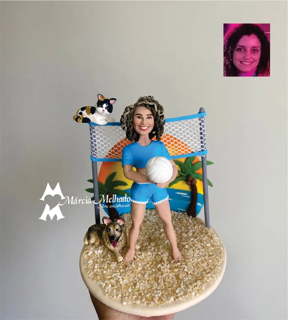 Boneca jogadora de vôlei de praia com cachorro e gato Boneca de biscuit com uniforme azul segurando bola de vôlei na areia, rede ao fundo, cachorro deitado e gato em cima da rede