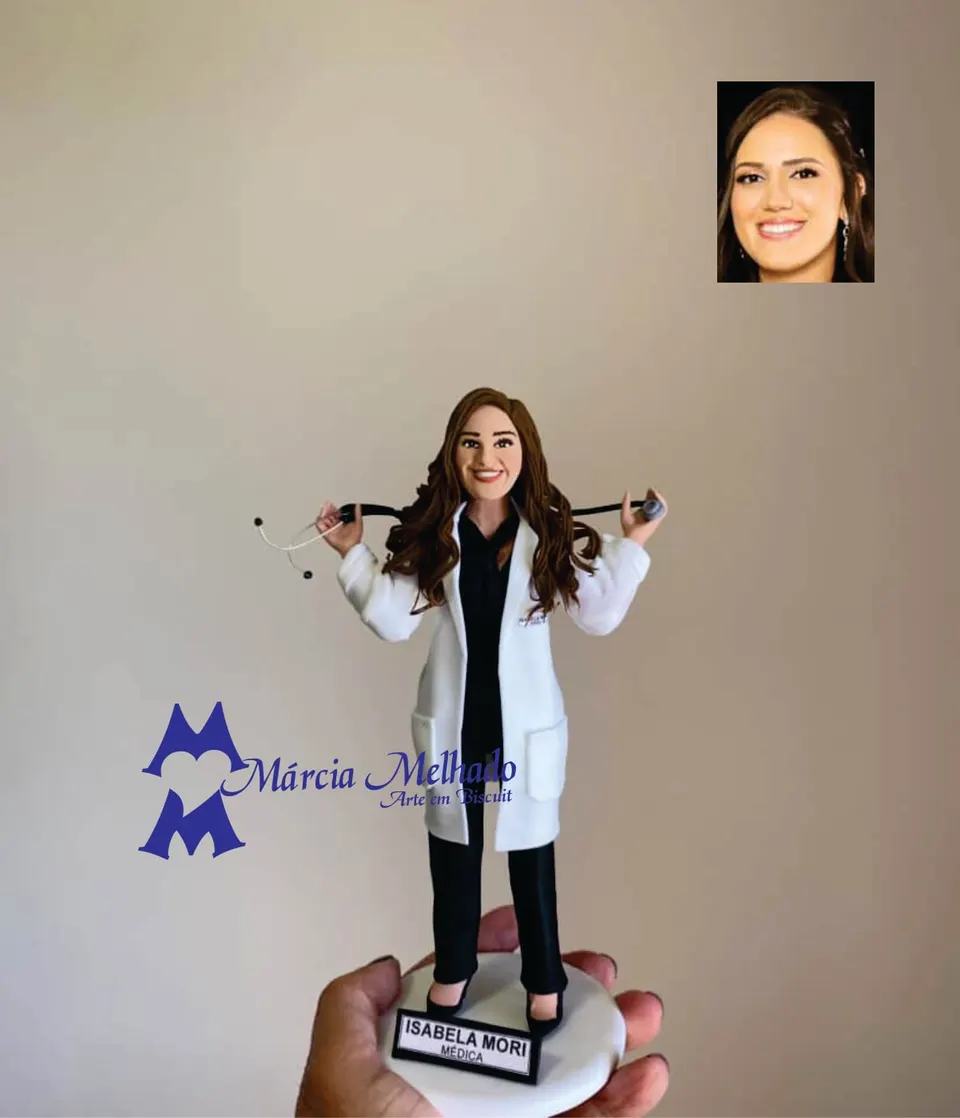 Boneca médica de jaleco branco com estetoscópio Boneca de biscuit de médica com jaleco branco, roupa preta e estetoscópio apoiado nos ombros, em base branca com plaquinha