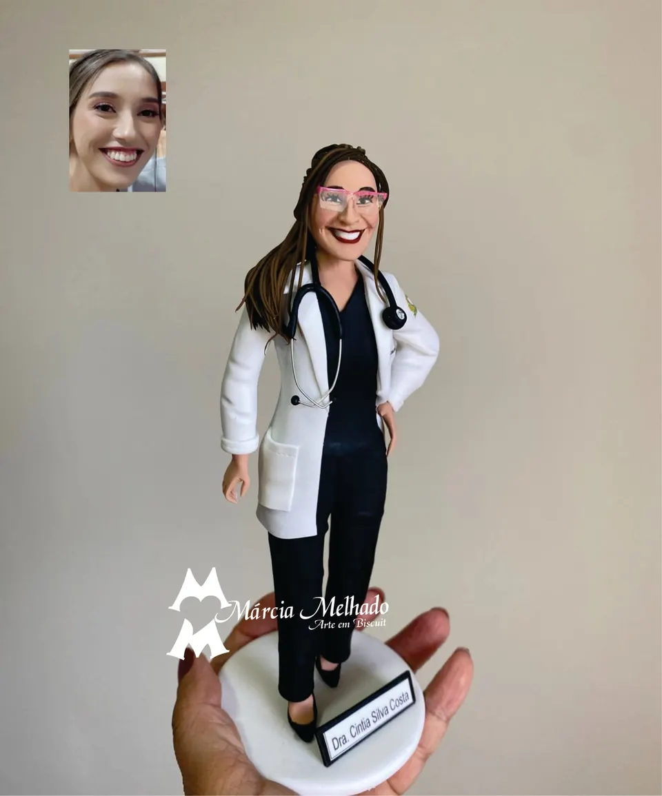 Boneca médica de jaleco branco com óculos rosa e estetoscópio preto Boneca de biscuit de médica com jaleco branco, óculos de armação rosa, estetoscópio preto no pescoço e roupa preta