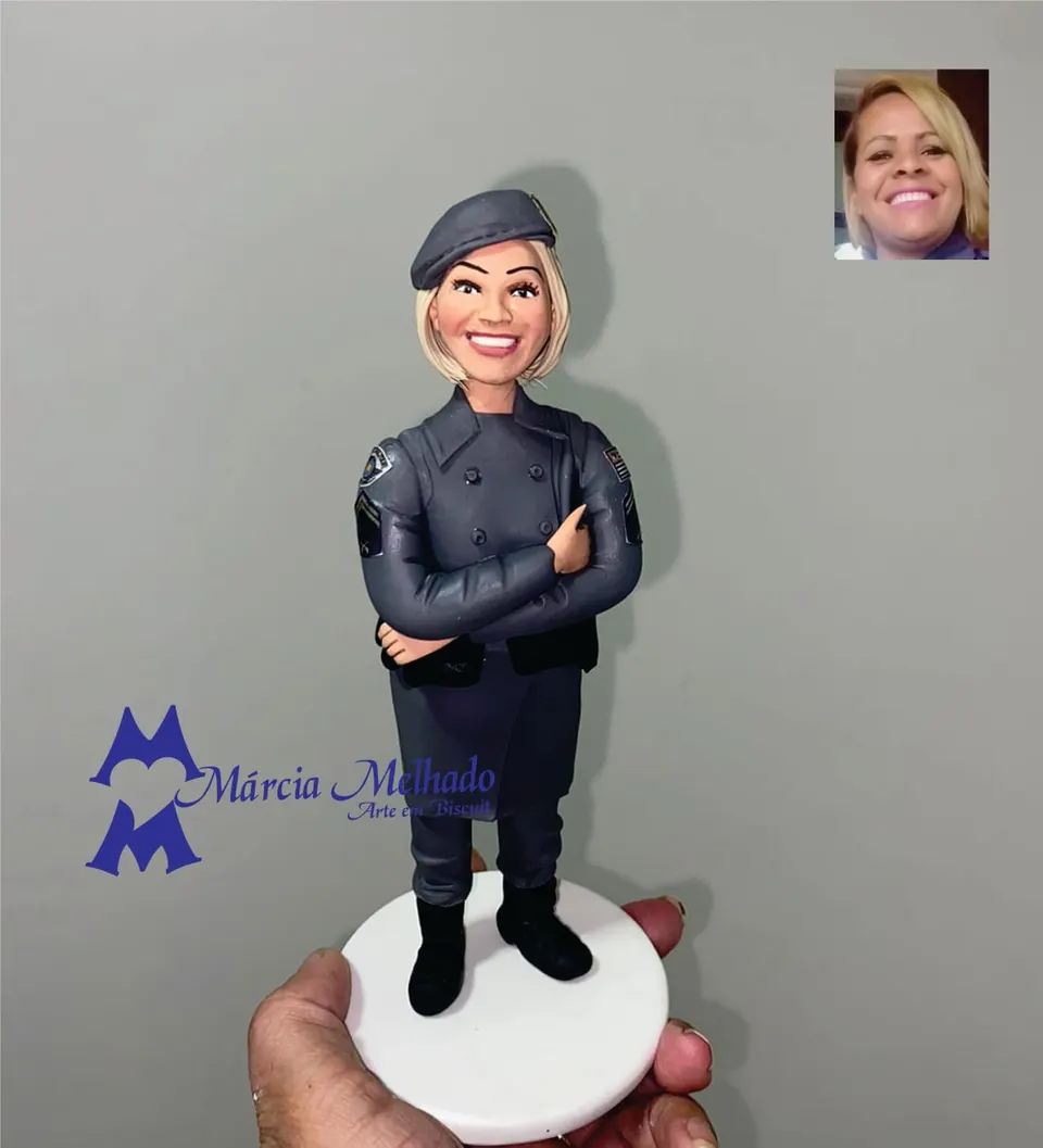 Boneca policial militar de boina com braços cruzados Boneca de biscuit de policial militar loira com boina, farda cinza com brasões nas mangas e braços cruzados