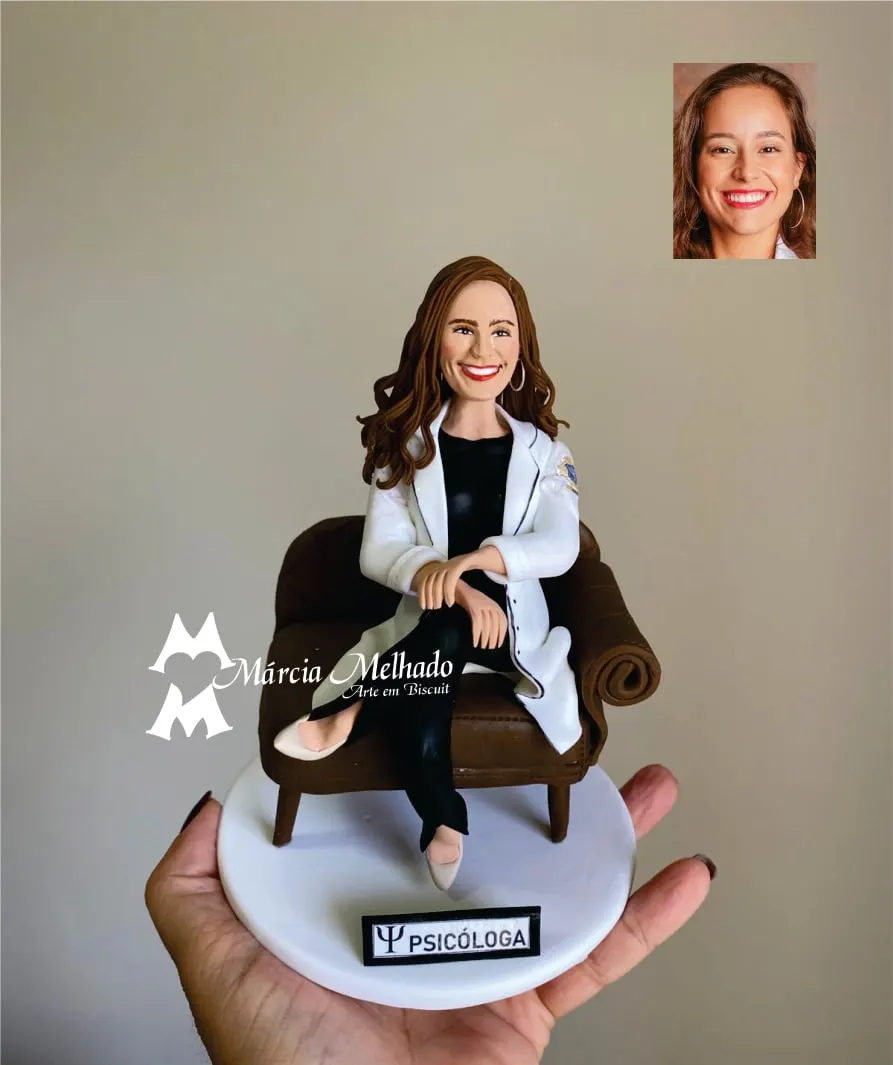Boneca psicóloga de jaleco branco sentada em poltrona Boneca de biscuit de psicóloga ruiva de jaleco branco sentada de pernas cruzadas numa poltrona marrom
