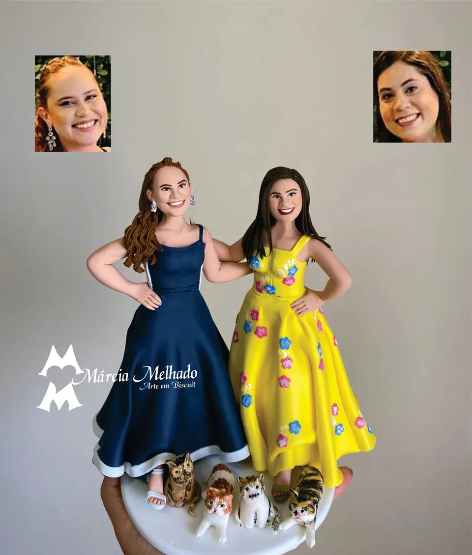 Bonecas de duas amigas de vestido de festa com cinco gatos Duas bonecas de biscuit abraçadas, uma de vestido azul-marinho e outra de vestido amarelo florido, com cinco gatos aos pés