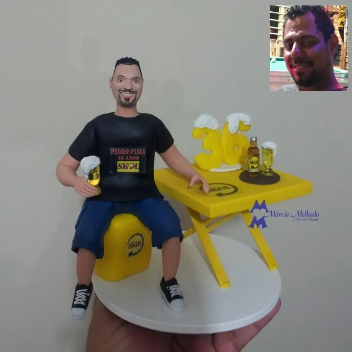 Boneco de aniversário 36 anos com cerveja e mesa de bar Boneco de camiseta preta sentado em engradado amarelo de cerveja com copo de chope e mesa de bar com número 36