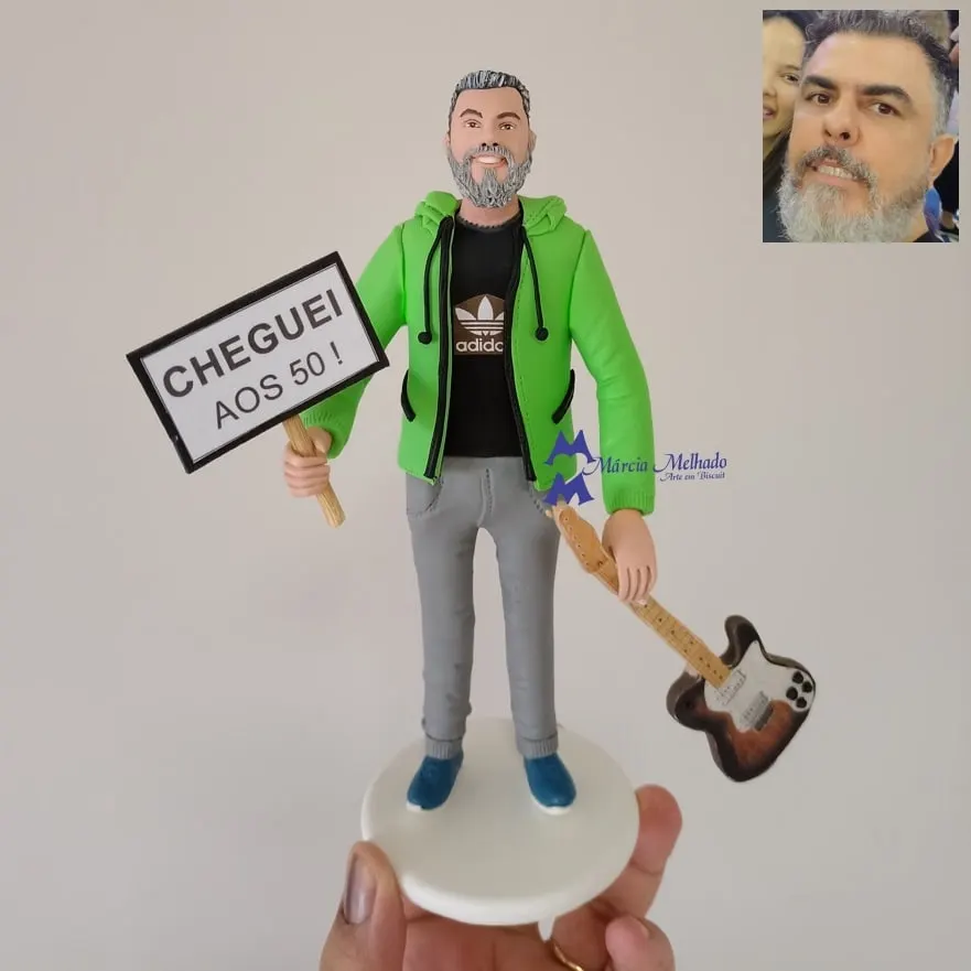 Boneco de aniversário 50 anos com guitarra e plaquinha Boneco de biscuit de homem grisalho com moletom verde segurando plaquinha Cheguei aos 50 e guitarra elétrica