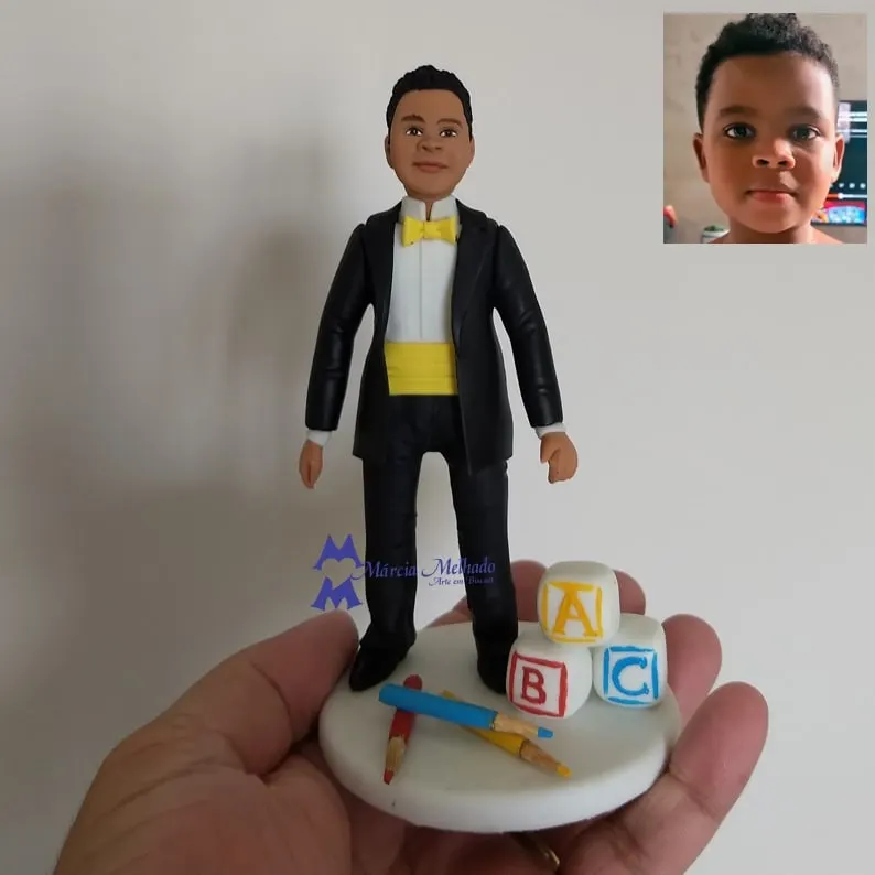 Boneco de formatura do ABC com smoking e cubos de letras Boneco de biscuit de menino com smoking preto e gravata borboleta amarela, com cubos das letras ABC e lápis de cor na base
