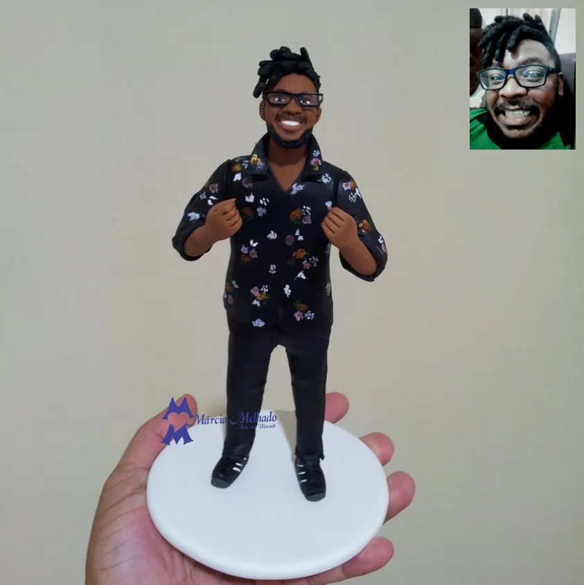 Boneco de homem com camisa florida e óculos Boneco de biscuit de homem com dreads, óculos e barba, camisa preta florida e calça preta, em pé sobre base branca redonda