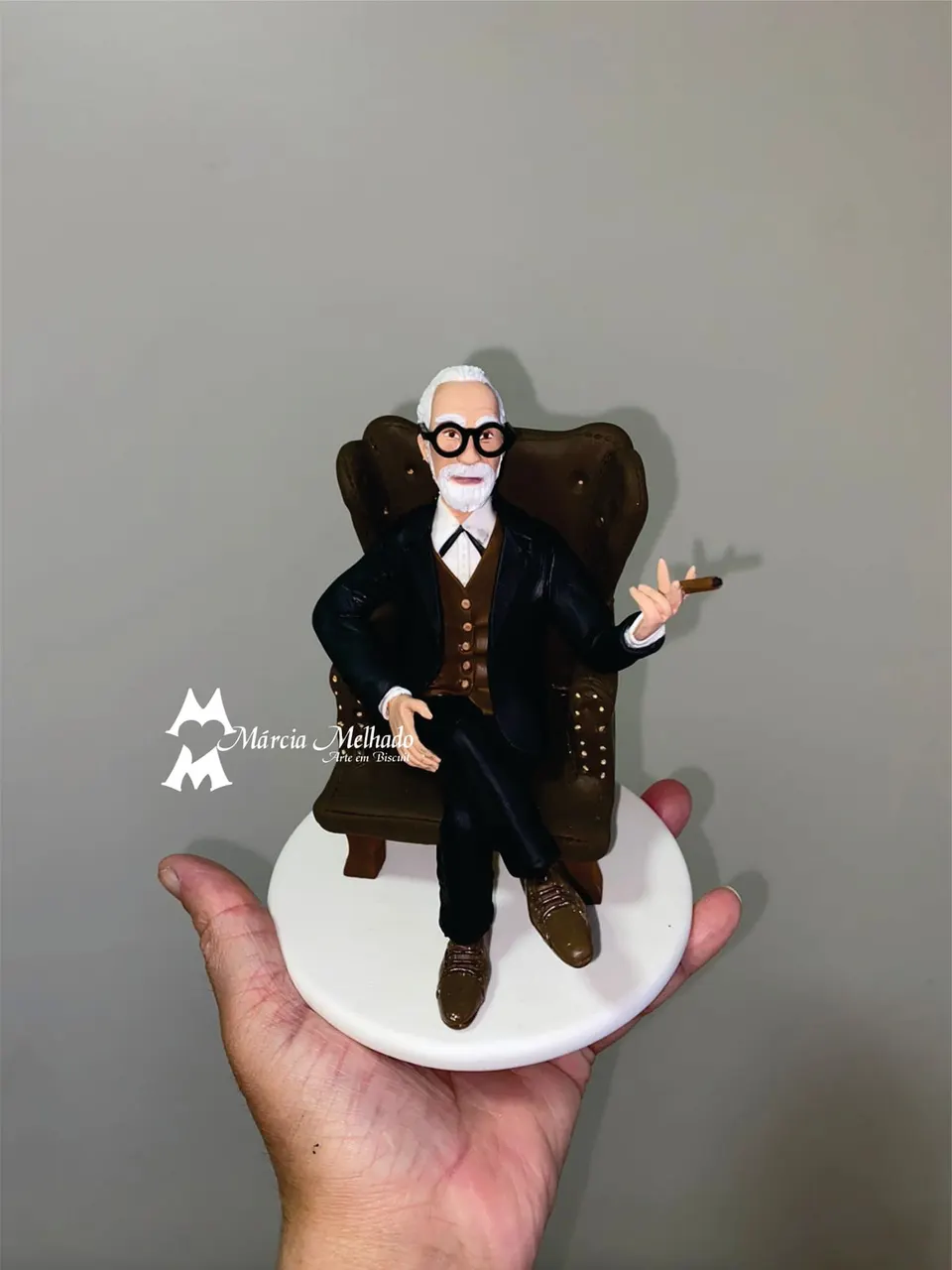 Boneco de senhor de terno sentado em poltrona com charuto Boneco de biscuit de senhor de barba branca e óculos redondos, de terno, sentado em poltrona marrom com charuto