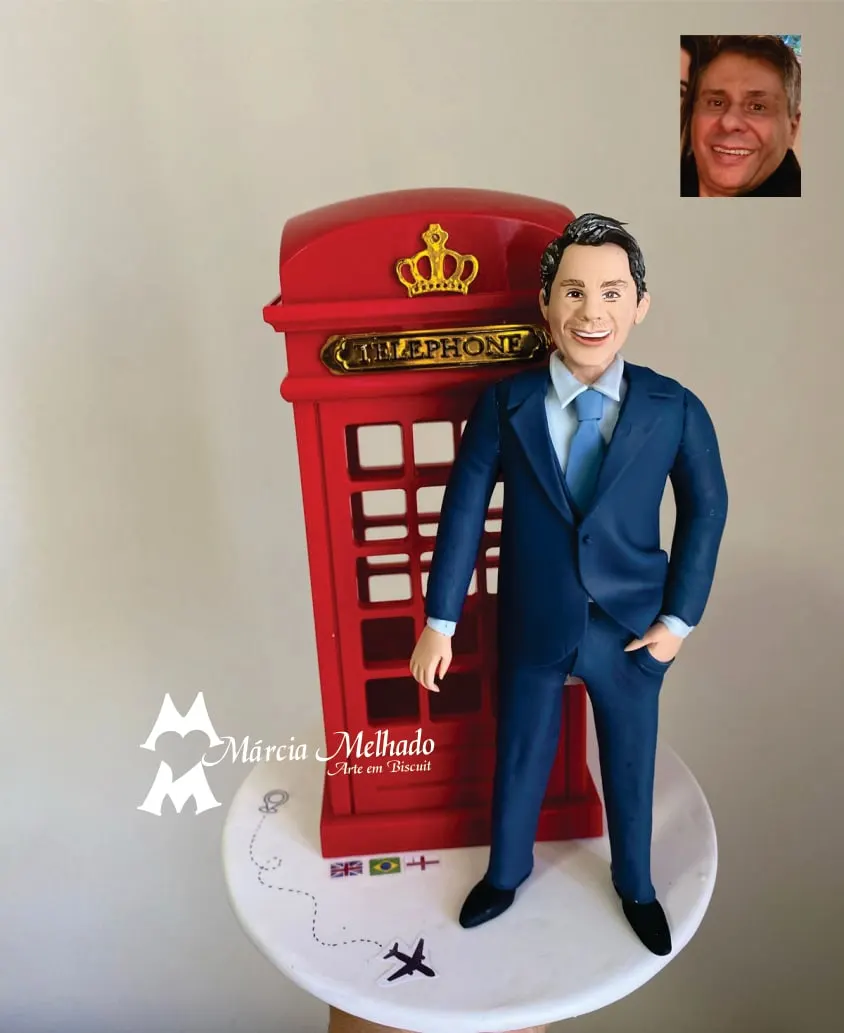 Boneco executivo de terno azul com cabine telefônica de Londres Boneco de biscuit de homem de terno azul-marinho ao lado de cabine telefônica vermelha de Londres com bandeiras na base