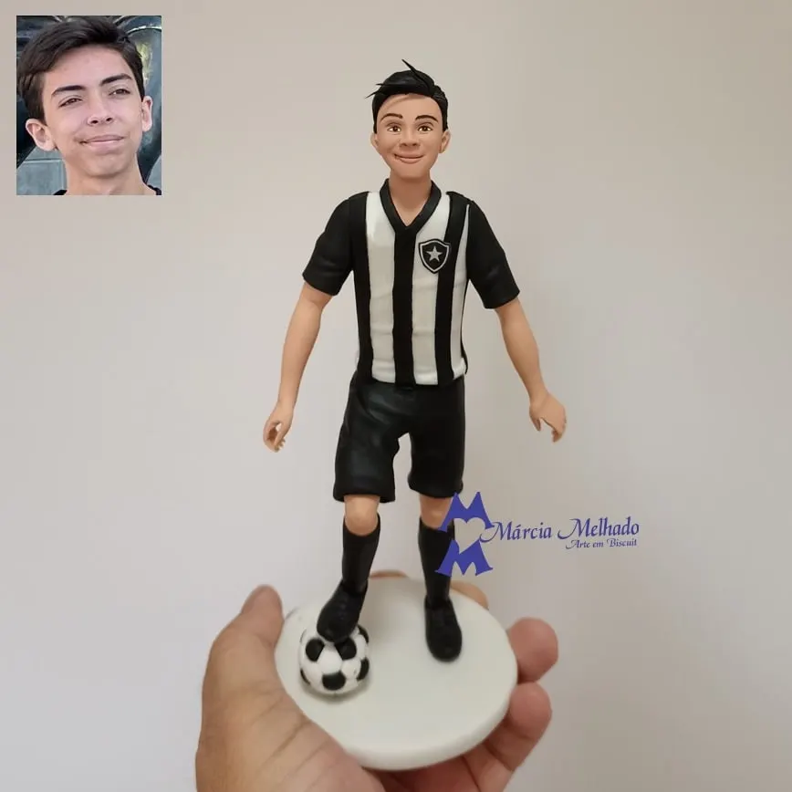 Boneco jogador de futebol com camisa listrada preta e branca Boneco de biscuit de jovem jogador de futebol com camisa listrada preta e branca e o pé apoiado na bola