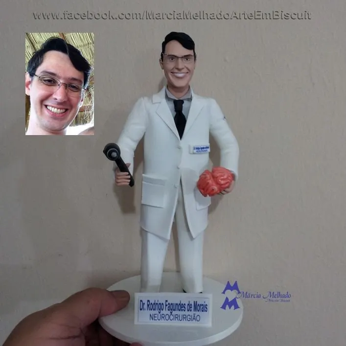 Boneco médico neurocirurgião com jaleco, martelo e cérebro Boneco de biscuit de médico neurocirurgião com jaleco branco e óculos segurando martelo de reflexos e um cérebro