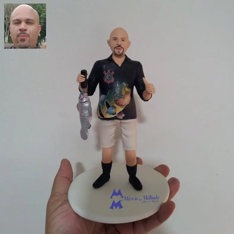 Boneco pescador com camisa do Corinthians segurando peixe Boneco de biscuit de pescador careca com camisa preta do Corinthians, bermuda bege, segurando um peixe e fazendo joinha