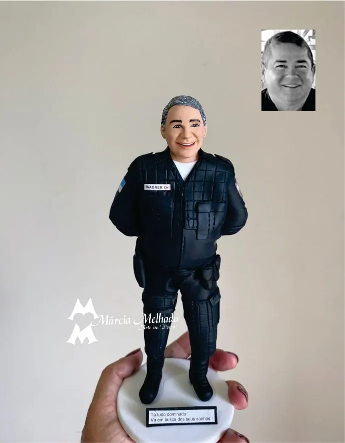 Boneco policial de farda tática preta com plaquinha de homenagem Boneco de biscuit de policial grisalho de farda tática preta, com as mãos atrás do corpo, sobre base branca com plaquinha