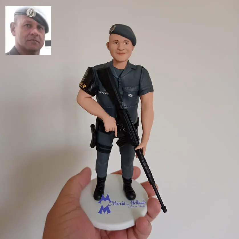 Boneco policial militar de boina com fuzil e braçadeira Boneco de biscuit de policial militar de farda cinza e boina, com braçadeira no braço e fuzil preto, sobre base branca