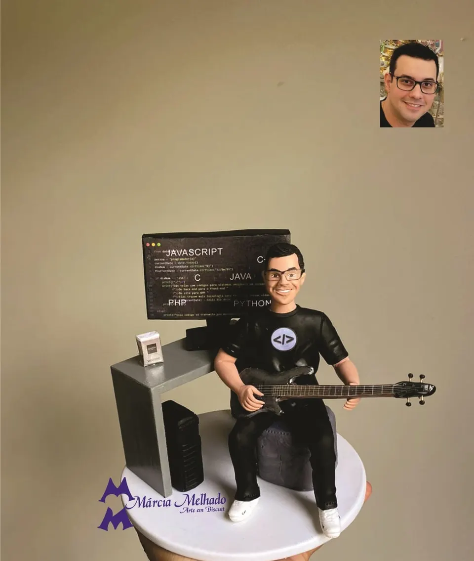 Boneco programador tocando baixo em frente ao computador Boneco de biscuit de óculos e camiseta preta tocando baixo sentado diante de mesa com monitor de códigos de programação