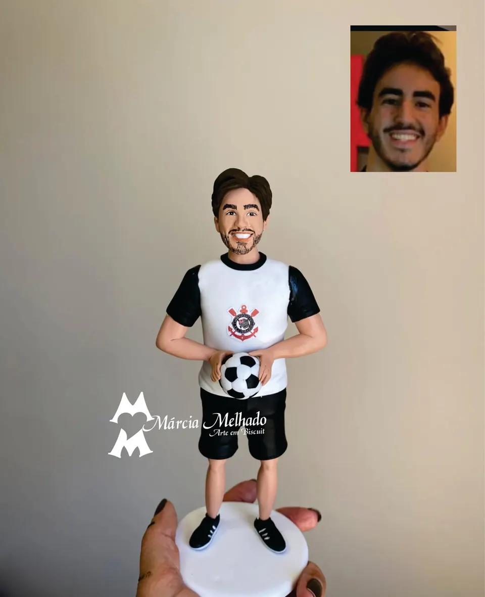 Boneco torcedor do Corinthians com bola de futebol Boneco de biscuit de rapaz barbudo com camisa do Corinthians e bermuda preta segurando bola de futebol