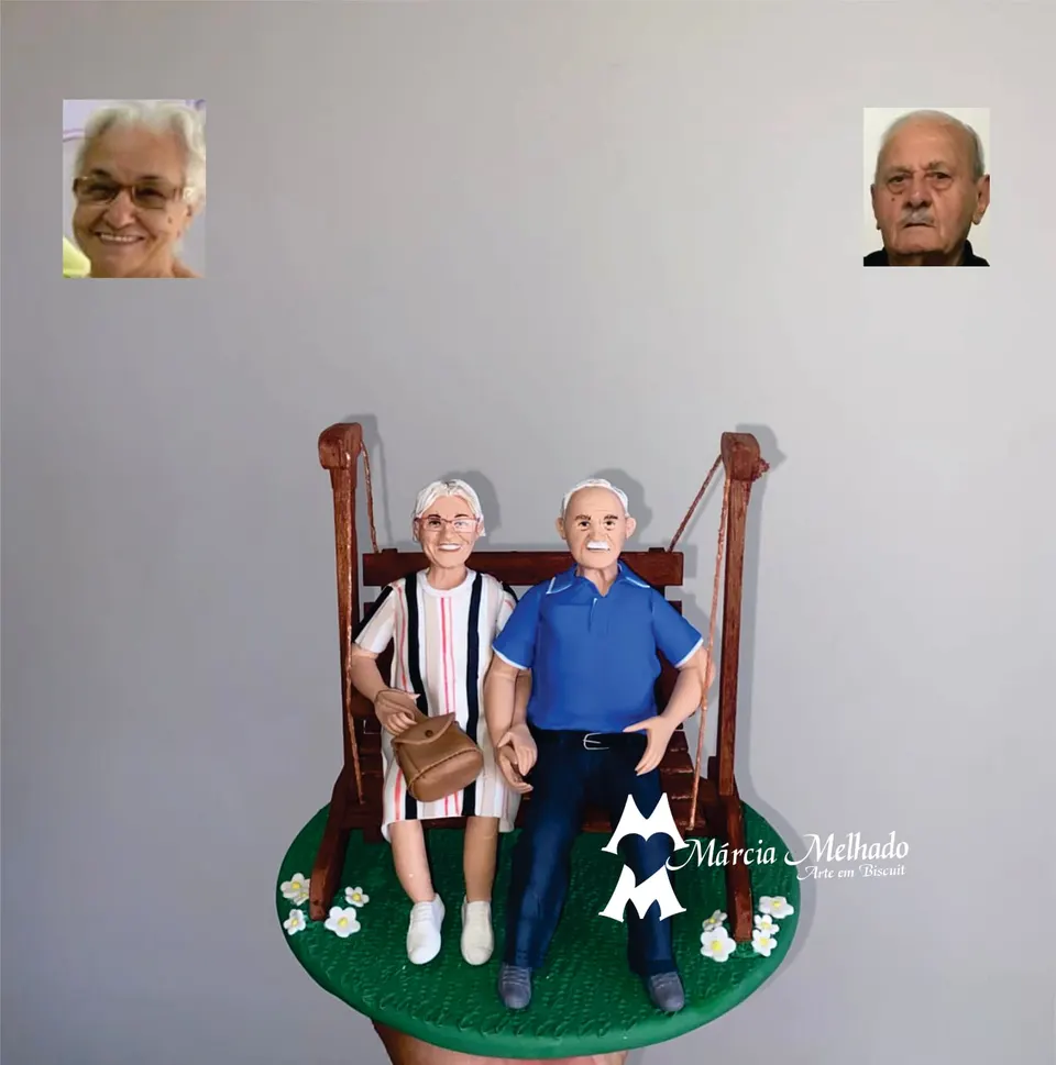 Bonecos de casal de idosos em balanço de madeira Casal de idosos de biscuit sentado de mãos dadas em um balanço de madeira sobre base de grama verde com margaridas