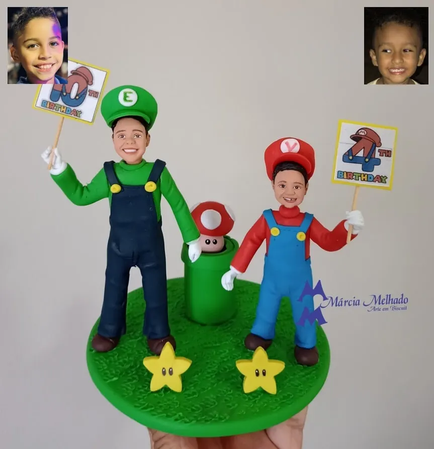 Bonecos de crianças vestidos de Mario e Luigi para aniversário Topo de bolo de biscuit com dois meninos vestidos de Luigi e Mario segurando plaquinhas de aniversário sobre base de grama