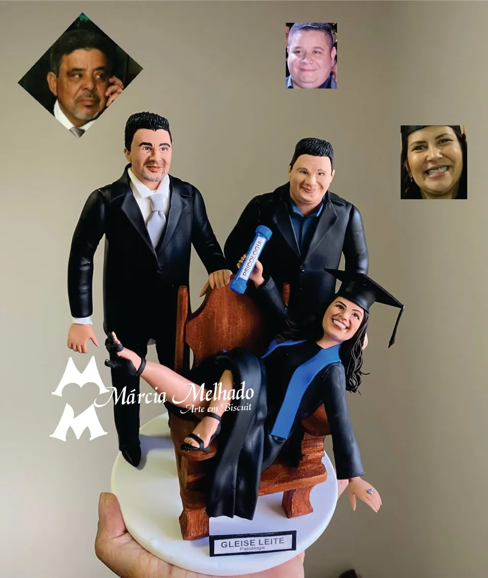Bonecos de formatura em psicologia com formanda na cadeira e dois homens Bonecos de biscuit de formanda em psicologia com beca e capelo em cadeira de madeira entre dois homens de terno preto.