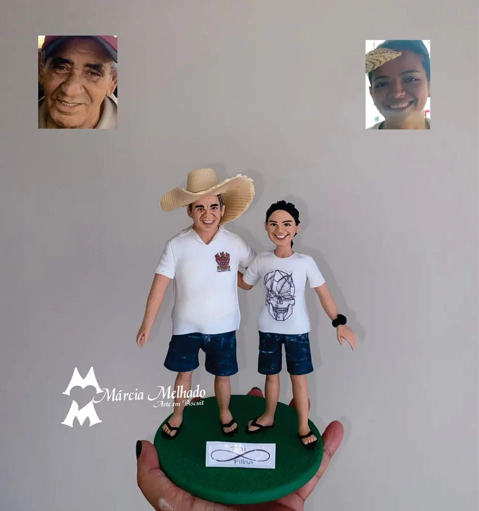 Bonecos de pai e filha com chapéu de palha e bermudas jeans Bonecos de biscuit de pai com chapéu de palha e filha de camiseta branca, ambos de bermuda jeans, abraçados em base verde