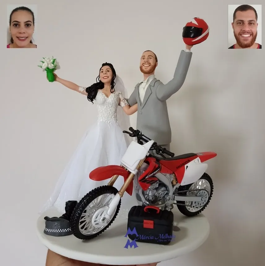 Noivinhos com moto de motocross Honda e capacete Noivos de biscuit de braços erguidos ao lado de moto de motocross Honda vermelha, com capacete, botas e caixa de ferramentas