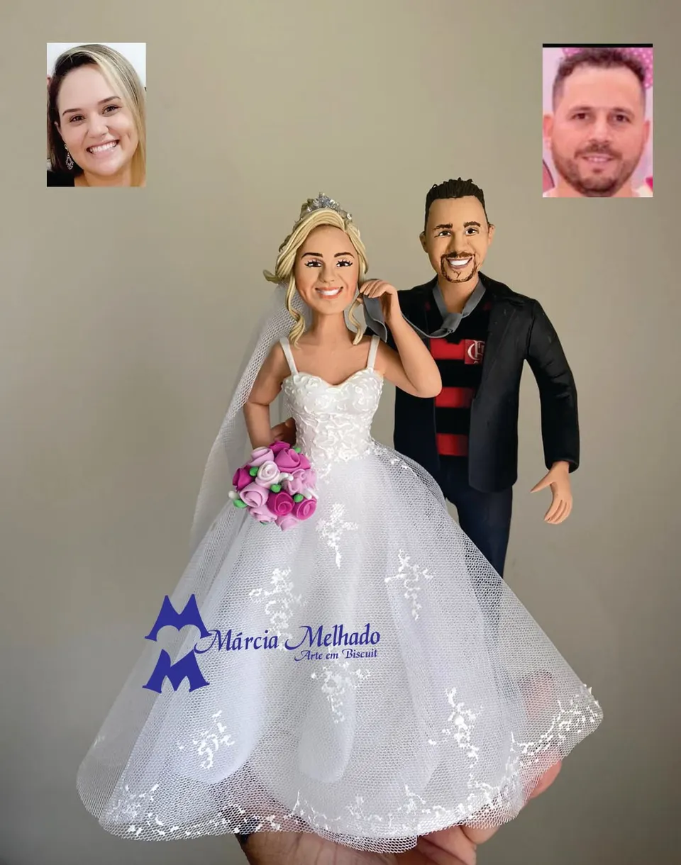 Noivinhos com noivo de camisa do Flamengo e buquê rosa Noivinhos de biscuit: noiva loira de tiara e vestido de renda com buquê rosa e noivo de blazer preto sobre camisa do Flamengo
