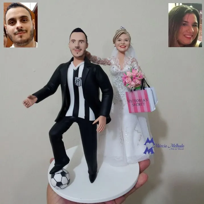 Noivinhos com noivo de camisa do Santos e noiva com sacola de compras Noivinhos de biscuit: noivo com camisa do Santos e pé na bola, noiva de vestido rendado com buquê rosa e sacola de compras