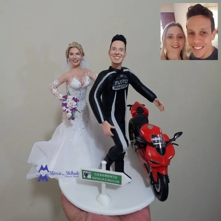 Noivinhos com noivo de macacão de motociclista e moto esportiva vermelha Noivo de macacão de motociclista ao lado de moto esportiva vermelha e noiva de vestido sereia com buquê roxo e placa