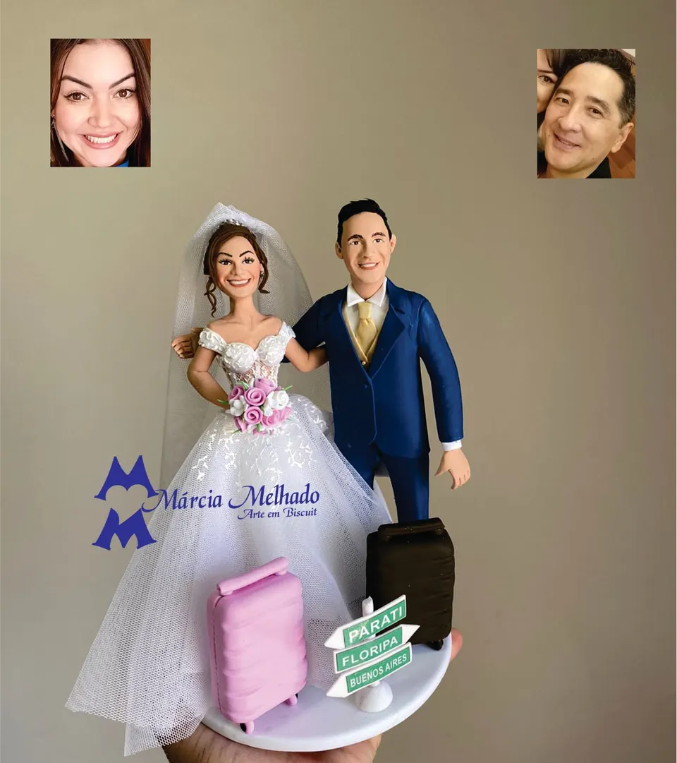Noivinhos viajantes com malas e placa de destinos Noivinhos de biscuit com noiva de vestido rendado, noivo de terno azul marinho, duas malas de viagem e placa de destinos