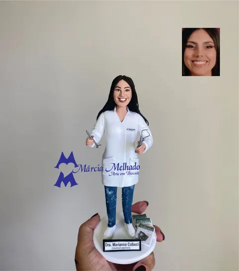 Boneca de biscuit de dentista com jaleco branco, calça jeans, instrumentos odontológicos nas mãos e livros de anatomia