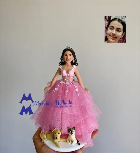 Boneca de biscuit debutante com tiara e vestido rosa de tule, com um cachorro caramelo e um gato deitados na base