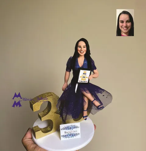 Boneca de biscuit de mulher de vestido azul de tule sentada no número 30 dourado, segurando um quadro Sou filha do Rei