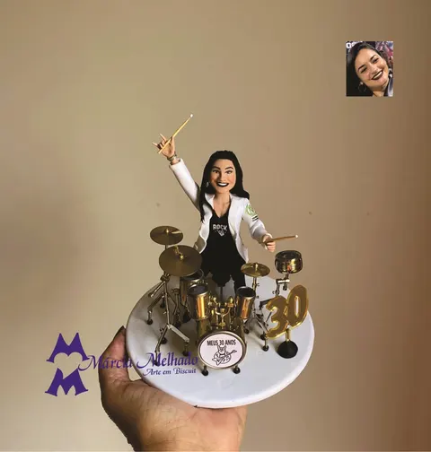 Boneca de biscuit de mulher de jaleco branco e camiseta de rock tocando bateria dourada, com número 30 na base