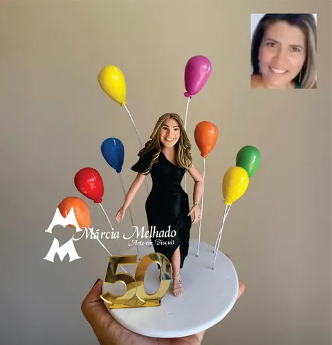 Boneca de biscuit loira com vestido preto de um ombro só entre balões coloridos, com o número 50 dourado na base
