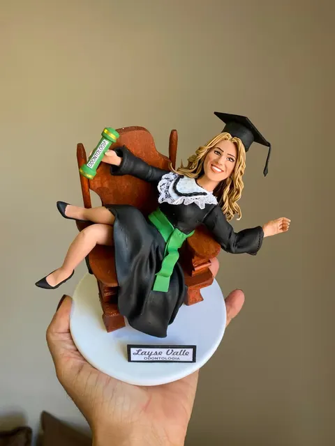 Boneca de biscuit formanda de odontologia reclinada em cadeira de madeira, erguendo o canudo verde