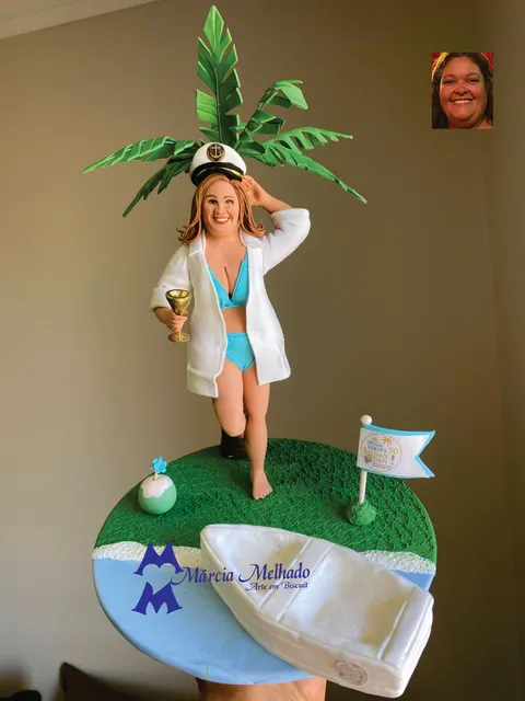 Boneca de biscuit de biquíni azul, camisa branca e quepe de capitão segurando taça numa ilha com coqueiro e lancha branca