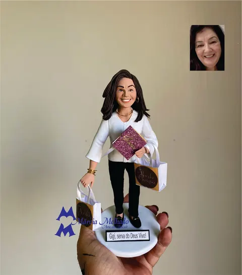 Boneca de biscuit de blusa branca e calça preta segurando Bíblia roxa com glitter e duas sacolas de compras