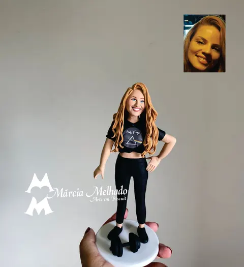 Boneca de biscuit de mulher ruiva com cropped preto do Pink Floyd, legging preta e tênis, com halter de academia na base