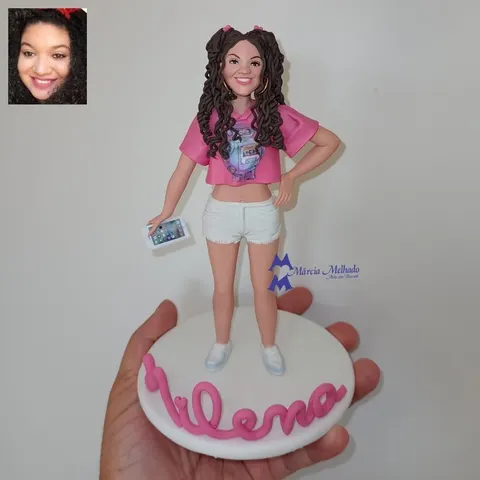 Boneca de biscuit jovem com cabelos cacheados em maria-chiquinhas, cropped rosa, shorts branco e celular na mão