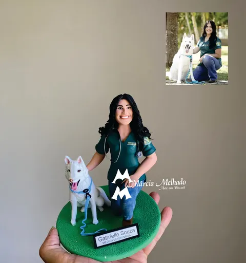 Boneca de biscuit de veterinária com uniforme verde e estetoscópio, ajoelhada ao lado de um cachorro branco com coleira azul