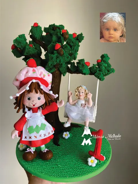 Boneca de biscuit da Moranguinho acenando ao lado de bebê loira no balanço preso à árvore de morangos, com número 1 vermelho