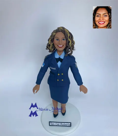 Boneca de biscuit de oficial militar com farda azul de gala, cabelos cacheados e sapatos pretos sobre base branca