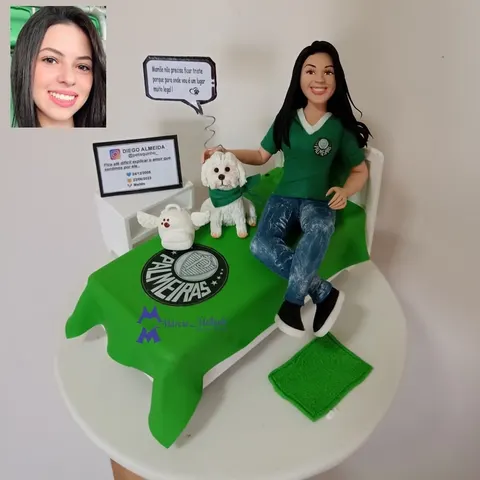 Boneca de biscuit com camisa do Palmeiras sentada na cama com colcha do time, acariciando cachorro branco de bandana verde