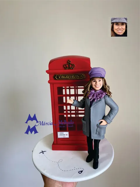 Boneca de biscuit com boina roxa e sobretudo cinza ao lado de uma cabine telefônica vermelha de Londres