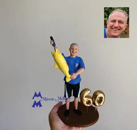Boneco de biscuit de pescador sorridente com camisa azul do Palmeiras segurando um peixe dourado, ao lado do número 60